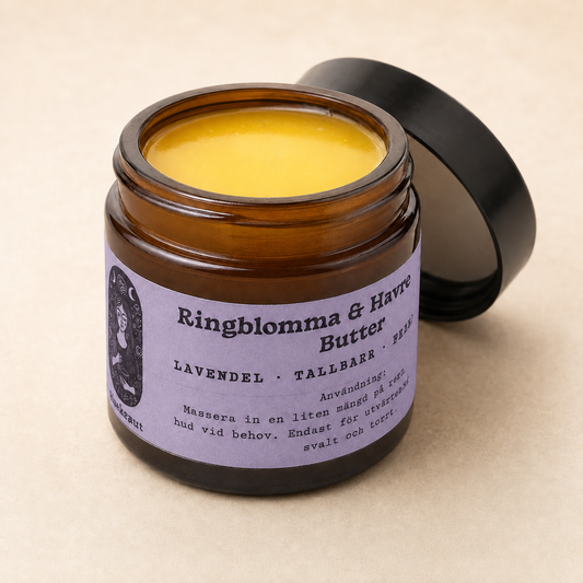 An open amber glass jar of forest scented calendula oat lotion butter with yellow balm visible inside, a black metal lid leaning behind it, and a lavender label with black text on a warm beige background.